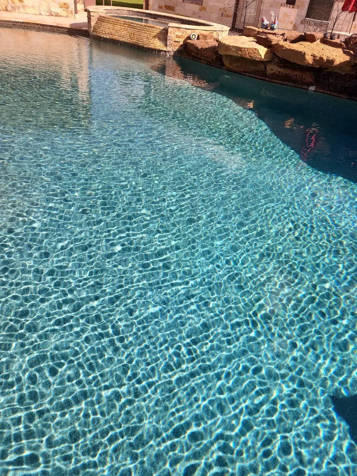 Crystal clear blue pool water in a Sam Houston Pools project, showing pristine water chemistry and pool finish