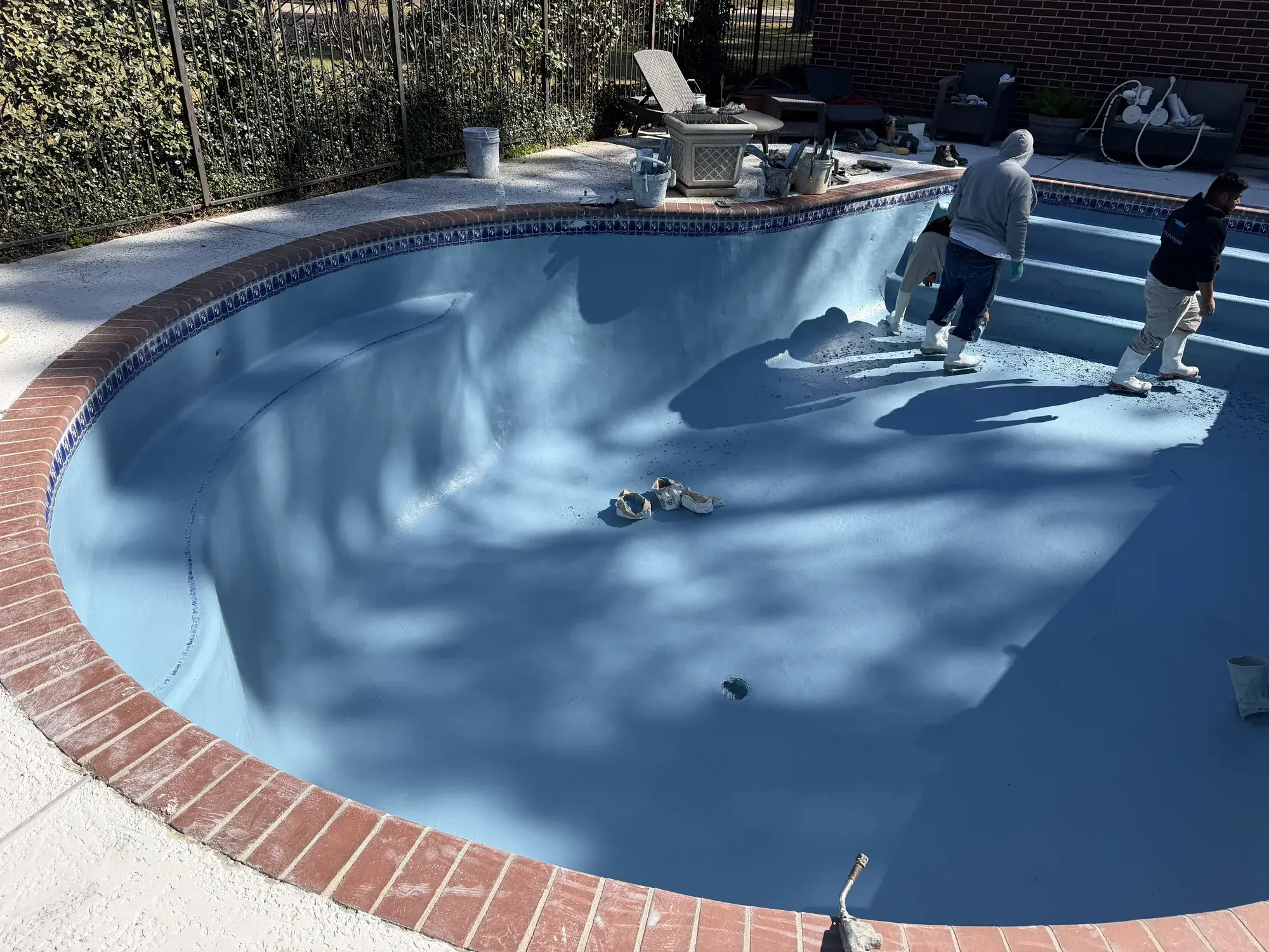 Portfolio photo of an in-ground pool build by a Houston-area pool builder, showing custom coping and waterline tile