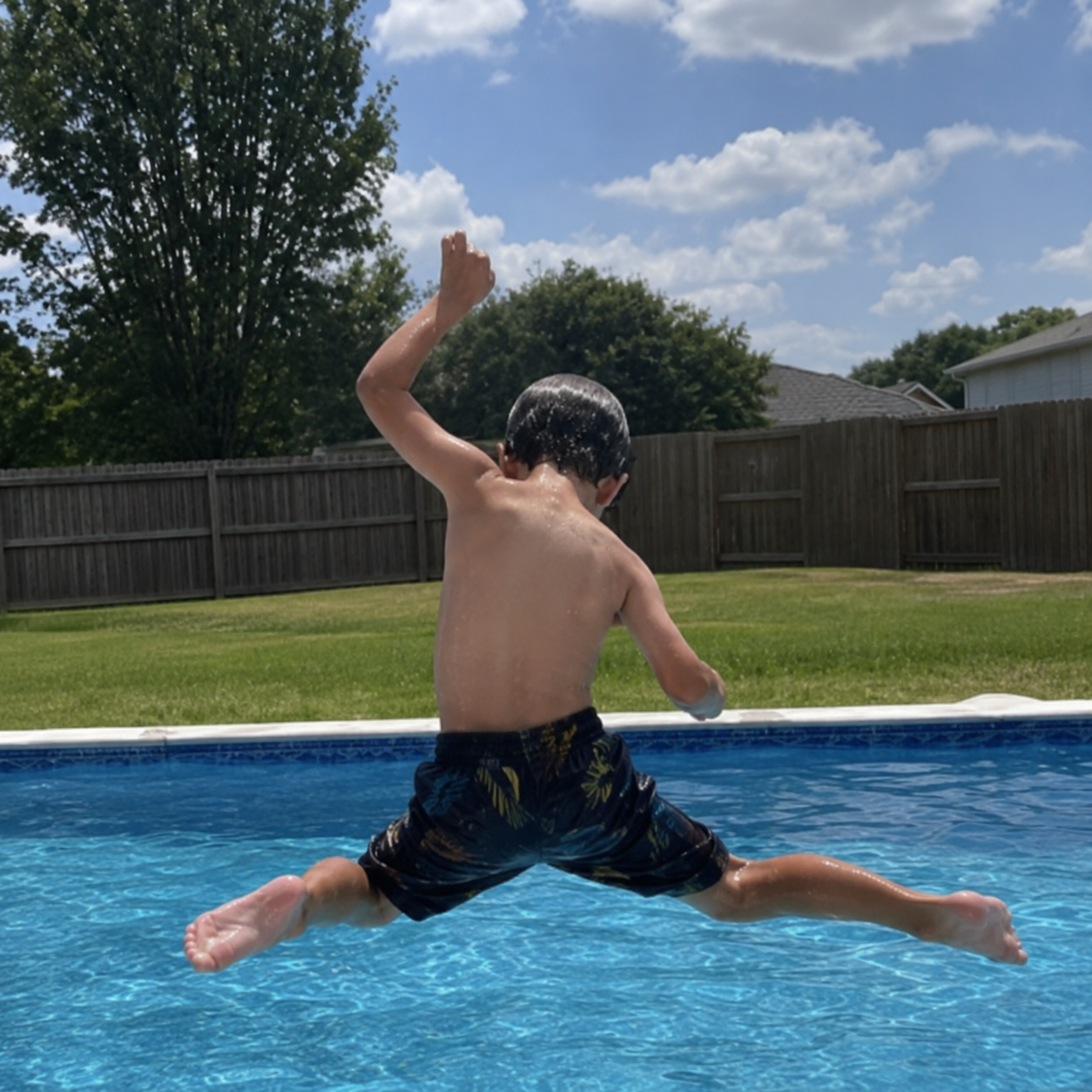 Kid mid-jump into a custom backyard pool built by Sam Houston Pools and Outdoors