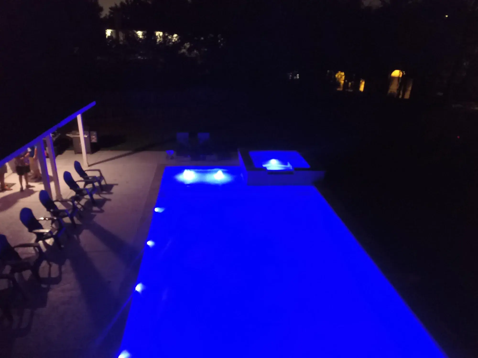 Backyard pool with blue LED lighting and patio lighting creating a night ambience in East Texas