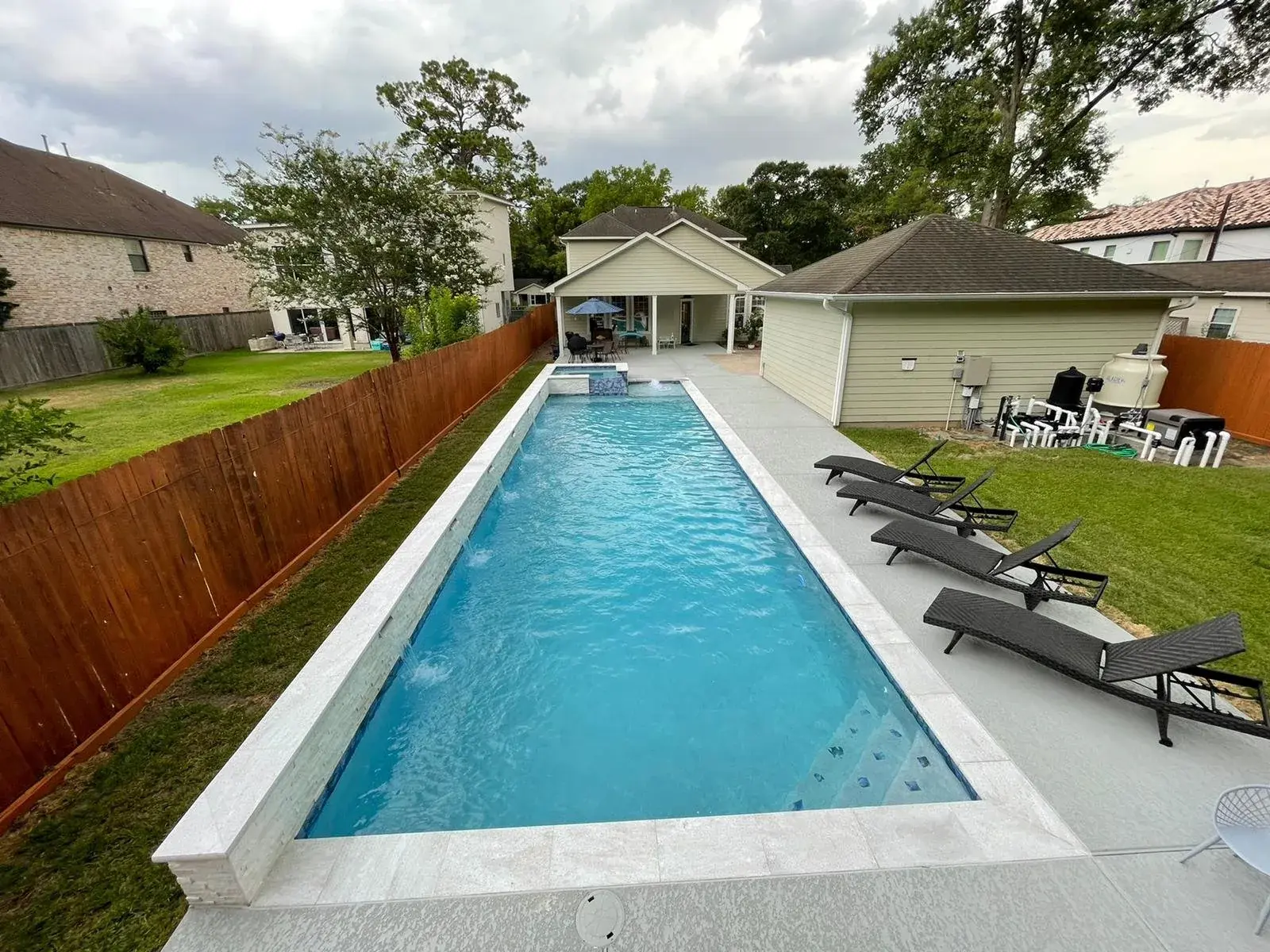 Long modern lap pool with attached spa combination and clean linear coping in a Houston-area backyard